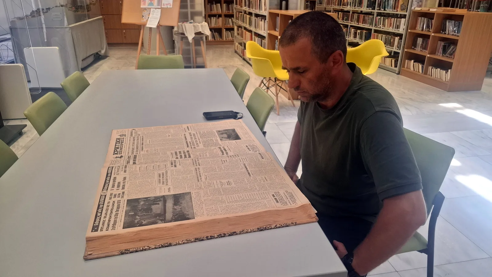 Tomasz Brzozowski przeglądający reprinty dawnych artykułów w bibliotece miejskiej w Rethymno
